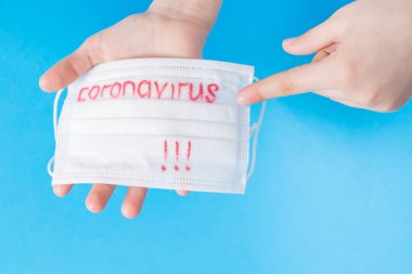 Dünya çapında koronavirüs salgını. Coronavirüs 'ün mavi arka planında bulunan beyaz koruyucu bir maske. Biyoteknoloji kavramı. Coronavirüs pnömonisi COVID-19.