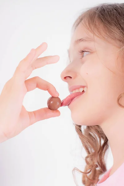 Vrolijk Meisje Speelt Eet Chocolade Ronde Snoepjes Een Lichte Achtergrond — Stockfoto