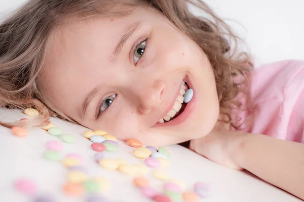 孩子和巧克力 一个快乐的女孩在明亮的背景上玩和吃着五颜六色的巧克力圆圆圆的糖果 免版税图库图片