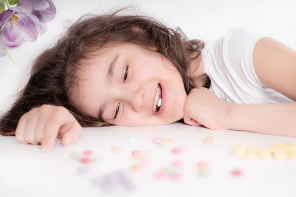 孩子和巧克力 一个快乐的女孩在明亮的背景上玩和吃着五颜六色的巧克力圆圆圆的糖果 免版税图库图片