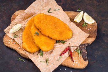 Mutfak tahtasının üzerinde limon dilimleri ve acı biberli tavuk şnitzel. Fast food. Fast food..