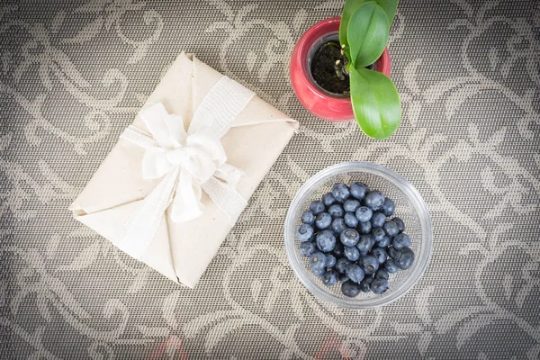 Composición de un regalo en paquete ecológico, arándanos en un tazón y — Foto de Stock