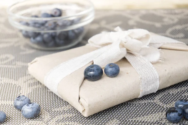 Composition of a gift in eco package and blueberries in a bowl — Stock Photo, Image