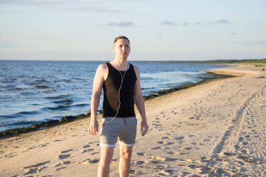Genç adam Baltık Denizi'nin sahilde spor için gidiyor 