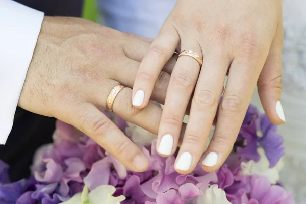 Hands of just married couple with golden wedding rings and sweet