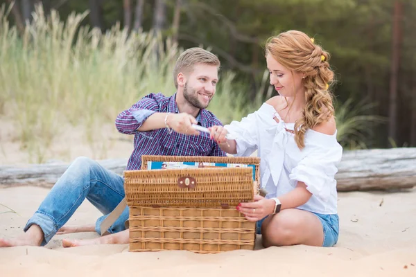 Young family couple on the beach near the sea having a picnic on — Stock Photo, Image