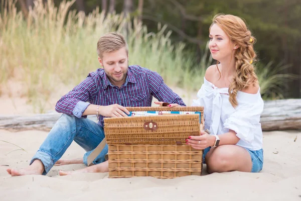 Young family couple on the beach near the sea having a picnic on — Stock Photo, Image