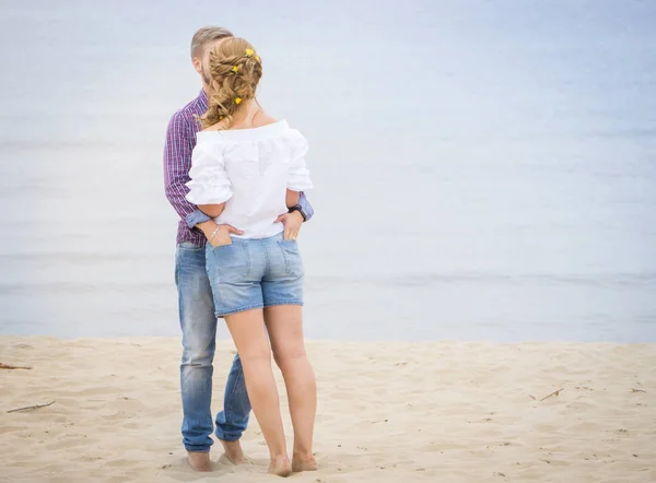 Jovem casal apaixonado andando ao longo do mar na praia segurando — Fotografia de Stock