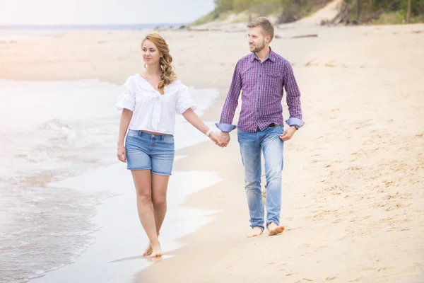 Молодая пара влюбленных прогулки вдоль моря на пляже холдинг — стоковое фото