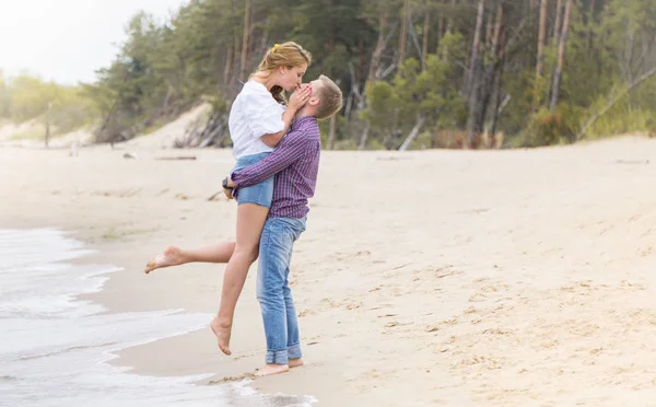 Giovane coppia innamorata passeggiando lungo il mare sulla spiaggia tenuta — Foto Stock