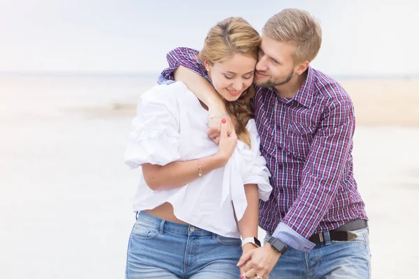 Jovem casal apaixonado andando ao longo do mar na praia segurando — Fotografia de Stock