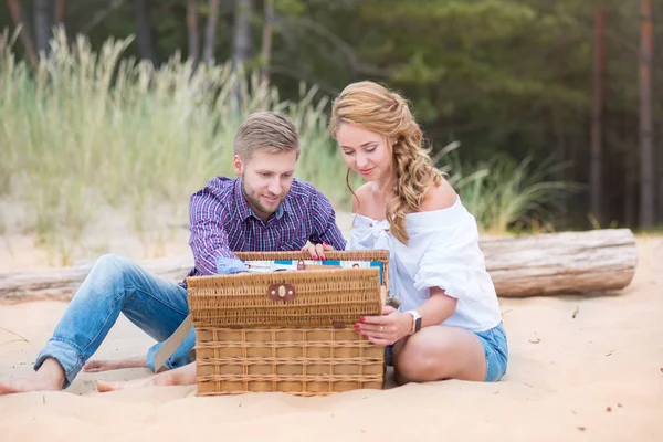 Young family couple having picnic on the beach near the sea, dri — Stock Photo, Image