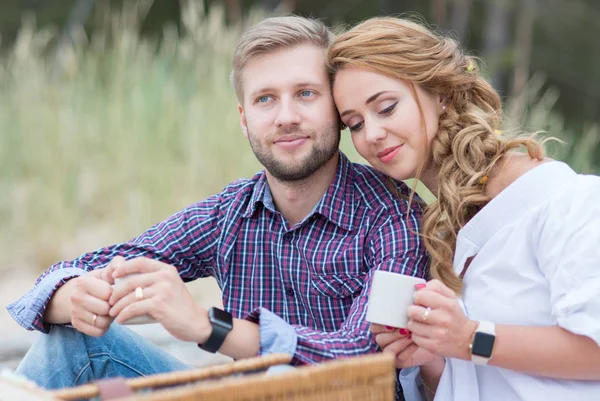 Young family couple having picnic on the beach near the sea, dri — Stock Photo, Image