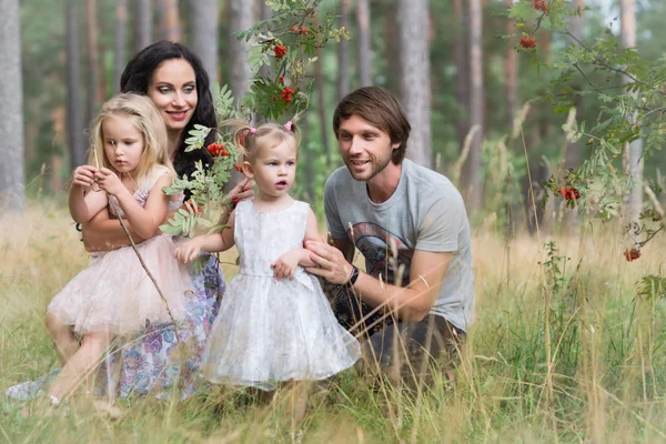 Beautiful young family with two daughters walking in the forest — Stock Photo, Image