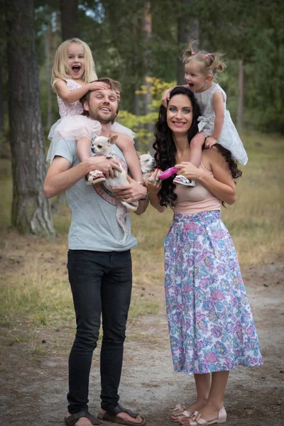 Hermosa familia joven con dos hijas caminando en el bosque — Foto de Stock