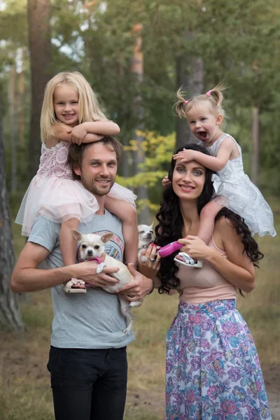 Hermosa familia joven con dos hijas caminando en el bosque — Foto de Stock