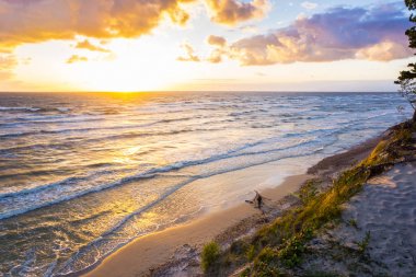Altın renkli bulutlu gökyüzü ile Baltık Denizi üzerinde güzel gün batımı 