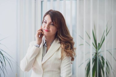 Şirket ofisindeki iş kadını bilgisayarda çalışıyor ve uzaktan iletişim kuruyor.