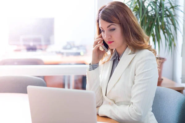 Business woman in company office working on laptop online and communicating remotely