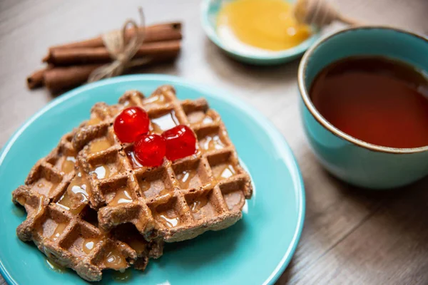 Vegan healthy waffles made in waffle maker with tea, honey and cinnamon
