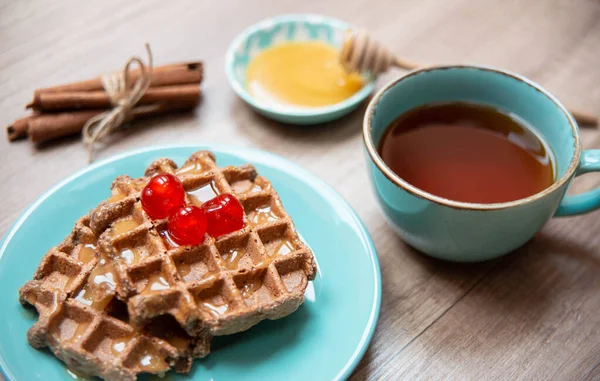 Vegan healthy waffles made in waffle maker with tea, honey and cinnamon