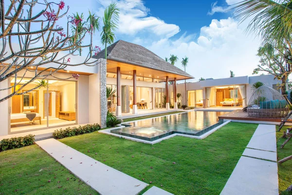 Interior and exterior design of pool villa which features living area, greenery garden, infinty swimming pool, wooden decking and sunbed surrounded by coconut tree — Stock Photo, Image