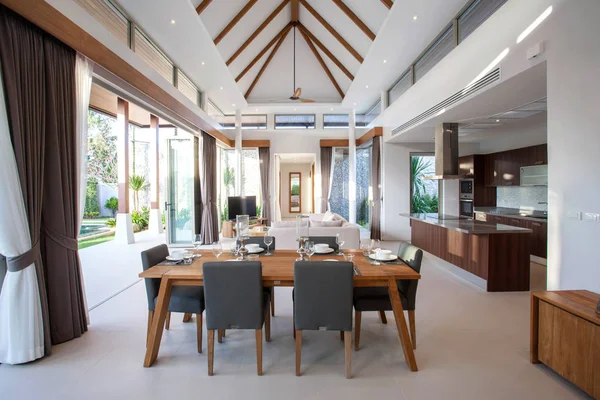 Design d'interni di lusso in soggiorno di ville con piscina. Spazio arioso e luminoso con soffitto alto e tavolo da pranzo in legno — Foto Stock