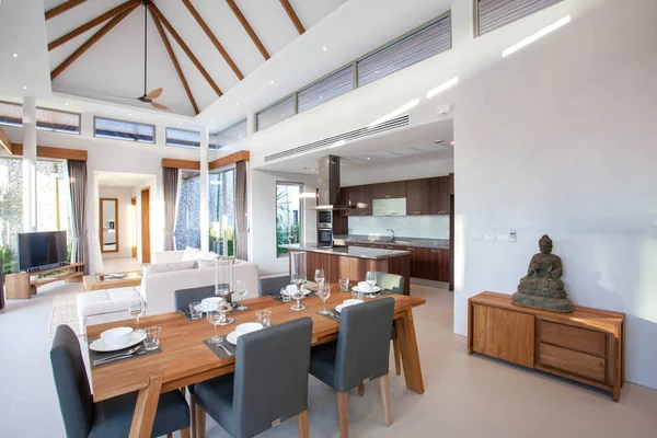 Diseño interior de lujo en salón de villas con piscina. Espacio aireado y luminoso con techo alto y mesa de comedor de madera — Foto de Stock