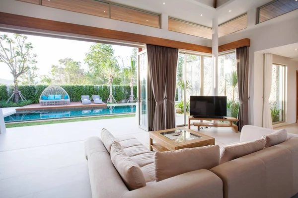 Diseño interior de lujo en salón de villas con piscina. Espacio aireado y luminoso con techo alto y mesa de comedor de madera —  Fotos de Stock