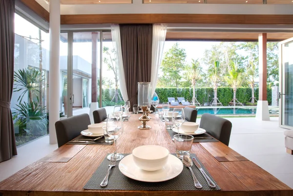 Design de interiores de luxo na sala de estar das moradias da piscina. Espaço arejado e brilhante com teto elevado e mesa de jantar de madeira — Fotografia de Stock