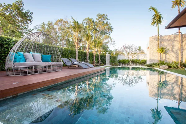 Diseño interior y exterior de la villa de la piscina que cuenta con sala de estar, jardín verde, piscina infinita, terraza de madera y tumbona rodeada de cocotero — Foto de Stock