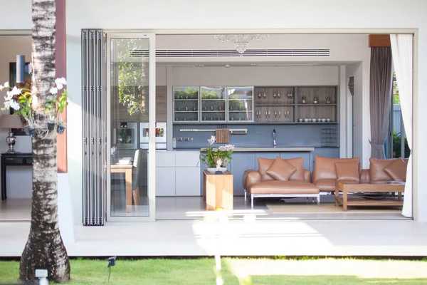 Diseño interior de lujo en salón de villas con piscina. Espacio aireado y luminoso con techo alto y mesa de comedor de madera — Foto de Stock