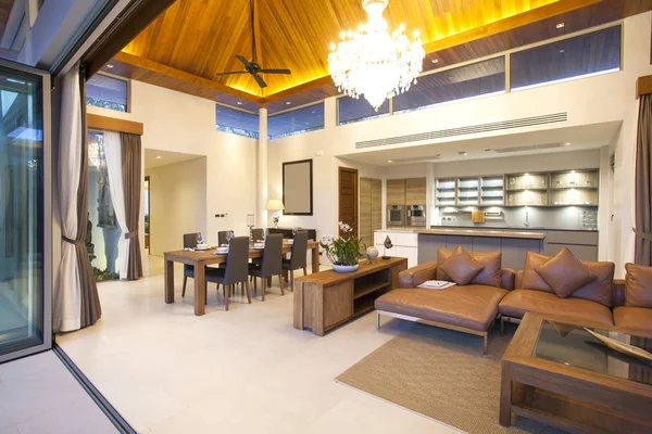 Design de interiores de luxo na sala de estar das moradias da piscina. Espaço arejado e brilhante com teto elevado e mesa de jantar de madeira — Fotografia de Stock