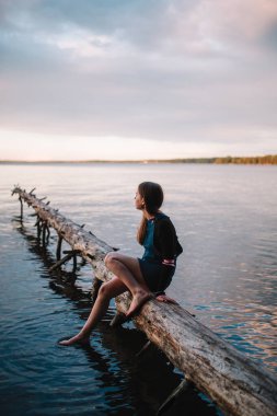 Genç güzel genç kız ormanda bir ışın bir göl üzerinde oturur