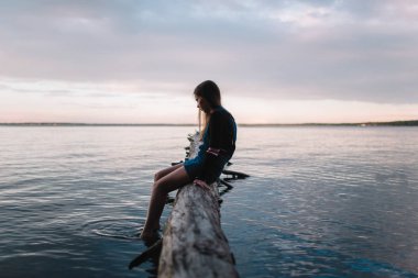 Genç güzel genç kız ormanda bir ışın bir göl üzerinde oturur