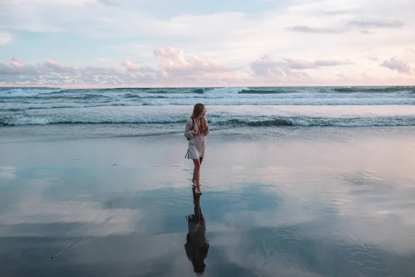 Chica rubia de pelo en un vestido rosa en la playa durante la puesta del sol, Indonesia, Bali —  Fotos de Stock