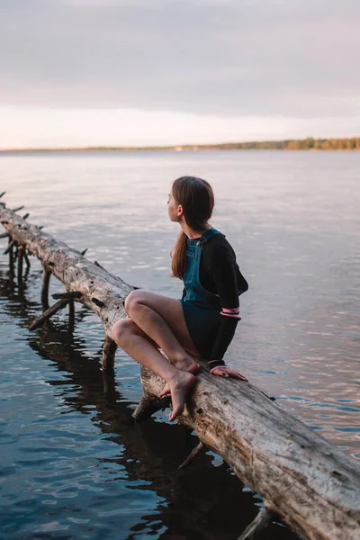 Genç güzel genç kız ormanda bir ışın bir göl üzerinde oturur