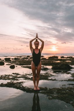 Pratik Yoga sahilde günbatımı sırasında genç çekici kız