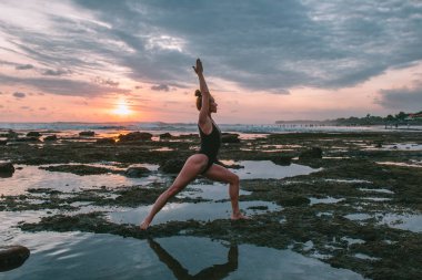 Pratik Yoga sahilde günbatımı sırasında genç çekici kız