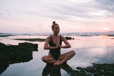 Pratik Yoga sahilde günbatımı sırasında genç çekici kız