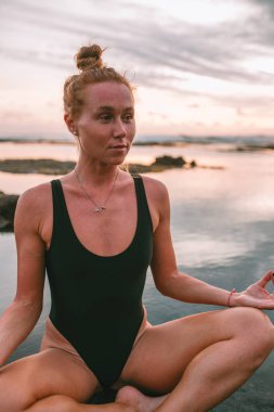 Pratik Yoga sahilde günbatımı sırasında genç çekici kız