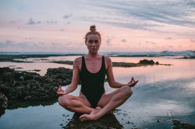 Pratik Yoga sahilde günbatımı sırasında genç çekici kız