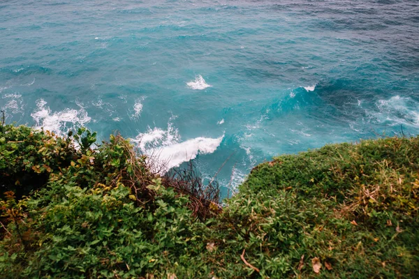 ocean waves under cliff with grass