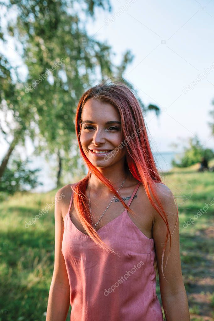 Portrait of young stylish girl with pink hair in the forest