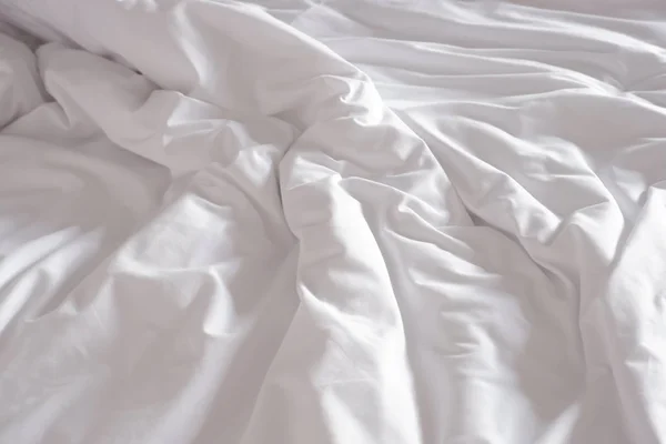 Белое измятое постельное белье в номере отеля — стоковое фото