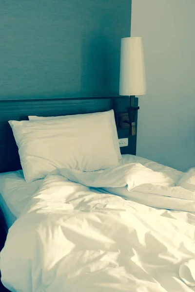 Lenzuolo bianco stropicciato e due cuscini disordinati in una camera d'albergo — Foto Stock