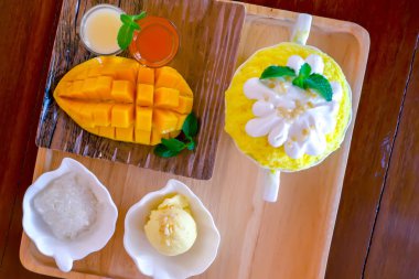 Bingsu (Kore tatlı tarzı) canlandırıcı tatlı mango meyveli pilav, dondurma ve ahşap tabakta tatlandırılmış süt ile servis edilir.