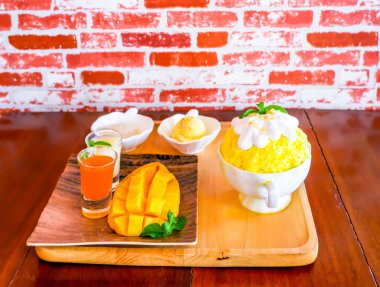 Bingsu (Kore tatlı tarzı) canlandırıcı tatlı mango meyveli pilav, dondurma ve ahşap tabakta tatlandırılmış süt ile servis edilir.