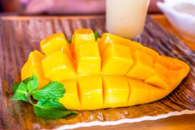 Mango meyvesi ferahlatıcı ve ahşap tabakta yoğunlaştırılmış süt.