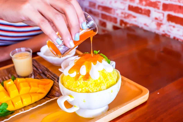 Nő kéz öntés mangó szirup jégre Bingsu (koreai desszert stílus) frissítő desszert mangó gyümölcs és ragadós rizs — Stock Fotó
